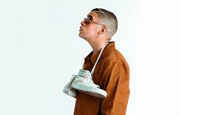 We have an extensive collection of amazing background images carefully chosen by our community. Bad Bunny Aesthetic With Hanging Shoes On Neck Looking Up Wearing Brown Coat In White Background Hd Music Wallpapers Hd Wallpapers Id 39076