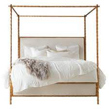 Wooden bed frames, which use wood slats running the width of the frame to support the bed, offer an ample foundation and go well when the rest of the framing elements, the footboard, headboard, and canopy, are also made of wood. Marilyn Modern Classic Gold Leaf White Linen Upholstered Wood Canopy Bed Queen Queen Kathy Kuo Home