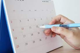 Mão com caneta escrevendo na data do calendário | Foto Premium