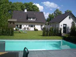 mooi zwembad in grote tuin met witte folie ook dit zwembad word door een solar lamellendek afgedekt om warmte te besparen en op te wekken zwembad tuin solar