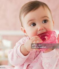Mixed Race Baby Girl Chewing On Plastic Toy High-Res Stock Photo