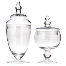 Each jar is made of clear glass and features a different size and a unique design that includes a spacious interior and a handled lid. Clear Glass Apothecary Jars Collection
