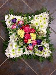 The beautiful display of blue and white funeral flowers in masculine colors will help illustrate the strength of your lost friend. Funeral Cushion Tribute Funeral Flowers Funeral Flower Arrangements Flower Arrangements