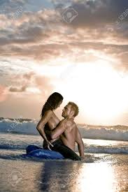 Young Sexy Couple On Beach With Sun Rising In Background Stock Photo,  Picture and Royalty Free Image. Image 7140336.