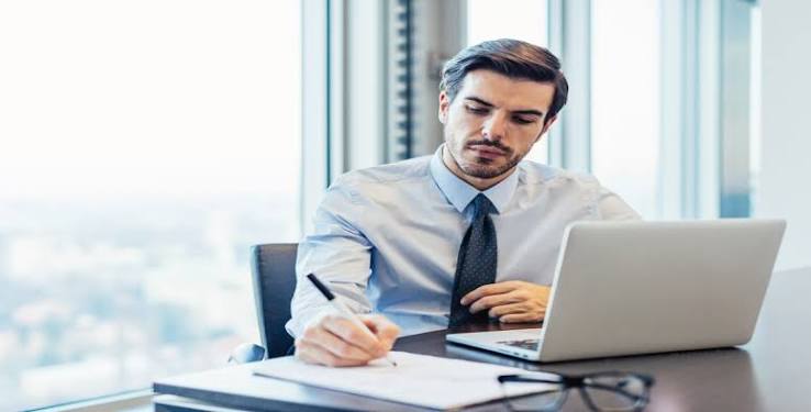 Advogado analisando documentos em escritório com laptop e livros jurídicos