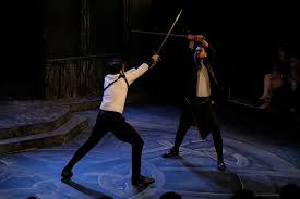 A sword fight in the sense that his opponents hold swords when they die. Stage Combat Wikipedia