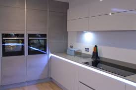 White kitchen elements create a unit, which forms a subtle background for the attached table and side cabinets. Second Nature And Burbidge True Handleless Kitchen In Ferndown Dorset