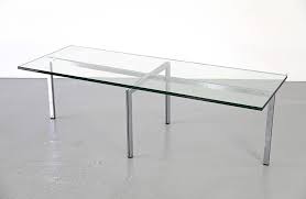 The table has a brass structure that holds a smoked mirror top and wide legs in brass and wood. Modern Coffee Table Adore Modern