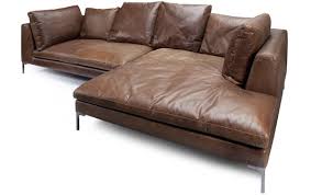 Modern corner fireplace in a sunny, peaceful living room interior with white walls and cozy pillows and blankets on a beige sofa. Iconic Interiors Siena Corner Sofa