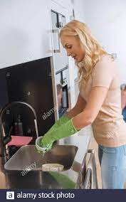 Attraktive Hausfrau in Gummihandschuhe Waschbecher in der Küche Waschbecken  Stockfotografie - Alamy
