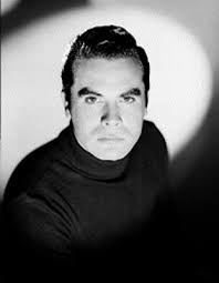 Fernando Casanova, actor, viste de traje y corbata, con cigarrillo  encendido en su mano derecha, retrato