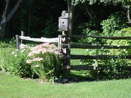 These split rail fences are perfect in all kinds of landscaping settings and would add a classic and casual touch to your yard and landscape design. Cedar Rail Fence With Bird House And Garden Beautiful Fence Landscaping Farm Landscaping Backyard Diy Projects
