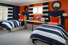 Vibrant Orange Accent Wall And Thick Navy And White Striped Linens In Boy S Bedroom With Pair Of Twin Beds Bedroom Orange Boys Room Blue Orange Kids Rooms