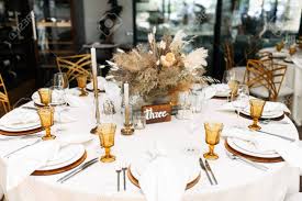 Maybe you would like to learn more about one of these? Wedding Banquet Stylish Table Design In Brown And Yellow Compositions Of Dried Flowers And Fluffy Spikelets In The Center Of The Round Table Tables Are Served With Cutlery And Colored Glasses Stock
