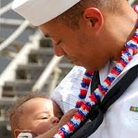 Damage Control Fireman Tyler Howard meets his son for the first, after  returning from deployment aboard the amphibious dock landing ship USS  Carter Hall (LSD 50).