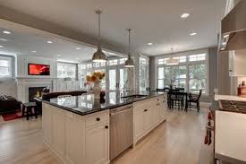 This bright dining room features a monumental wooden dining table with green leather dining chairs with black legs. Modern Bungalow Open Concept Kitchen Living Room Kitchen Design Kitchen Island Design