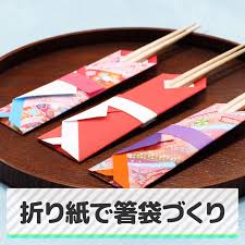 箸袋にもお正月らしさを つくり方をチェック 着物のお箸袋 1 折り紙2枚を1cm程ずらして重ね お箸袋をのせる 2 そのうえに箸を1本置いて 中心を決める 3 左からお箸袋に合わせて折り 右側も同様に折る 4 下側も箸袋に合わせて折ったら箸袋を取り 右側が