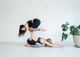 Lie flat on your bed and stack two pillows underneath your knees. 6 Partner Yoga Moves Anyone Can Do Om The City