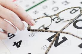 Close Up Of Womans Hands Holding Glasses Above Eye Chart D1028_32_498