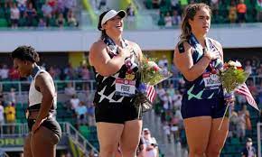Olympic team during the trials — shifted to face the stands rather than the flag before holding up a black shirt that reads activist athlete. E1n6qll Ihz7km