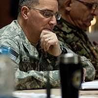 Trinidad and Tobago Defence Force MAJ Peter Sealy, left rear, and TTDF CMDR  Kirton Huggins, right rear, have a laugh with TTDF CPT Elizabeth Williams,  seated, during the Initial Planning Conference for