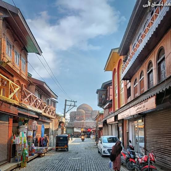 Narrow cobblestone street in old Srinagar with traditional wooden buildings and shuttered windows