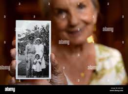 Shirley Waldron Nied holds a photograph of her family at Hickam Field at  Joint Base Pearl Harbor Hickam