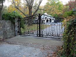 The wrought iron entry gate bears all resemblances to a palace gate with a touch of gold against the dark black background. This Wrought Iron Driveway Gate Features Traditional Scroll Designs And A Thicker Than Usual Wrought Iron Driveway Gates Driveway Gate Wrought Iron Front Door