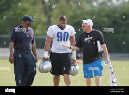 Detroit Lions defensive tackle Ndamukong Suh (90) walks with agent Roosevelt  Barnes, left, and Bill Keenist, Lions' senior VP of Communications after  Suhs first football workout at the team's summer camp in