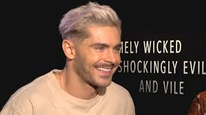 In the snap, a few wisps of his lightened hair poke out from under a black beanie while he grips to a wall. Zac Efron Explains His Platinum Blonde Hair And Not Quite Brad Pitt Abs Exclusive Entertainment Tonight