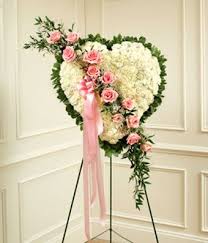 Heart shaped sympathy flower arrangement with white roses near a tree. Solid White Floral Standing Heart At From You Flowers Funeral Flower Arrangements Funeral Floral Arrangements Funeral Flowers