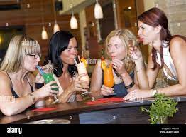Model release, Vier junge Frauen sitzen mit Cocktails an der Bar - four  women in cocktail bar Stock Photo - Alamy