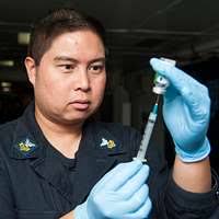 Hospital Corpsman 1st Class Samuel Karr administers a smallpox vaccine to  Gunner's Mate Seaman Brandon Tokarski during a ship-wide mass smallpox  inoculation.