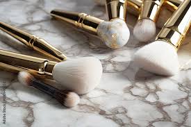 golden makeup brushes on marble