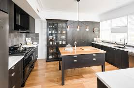 Black kitchen cabinets are tempered here with the light wood island and countertops. Kitchens With Black Cabinets