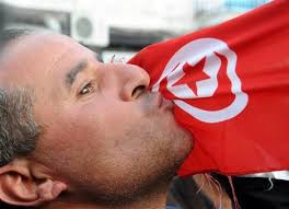 photo: AP / Hassene Dridi. A man kisses the Tunisian flag during a demonstration in Tunis, Tunisia, against high - 1b864a7e0a4912885966f328fae1-grande
