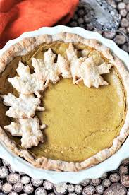 a whole easy vegan pumpkin pie in a pie plate with 6 pie crust leaves on