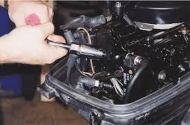 A Spark Plug Being Removed From An Outboard Motor