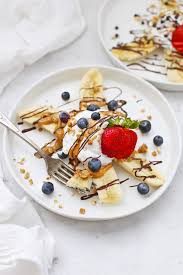 Bananas cut in half · 1/2 cup greek yogurt to each · almond slices · granola · dried coconut · blueberries · raspberries · blackberries Healthy Banana Splits Vegan Paleo One Lovely Life