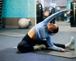 Image of someone doing static stretches for their legs in a gym