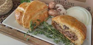 Cheeseburger Wellington on a plate garnished with onions mushrooms and thyme