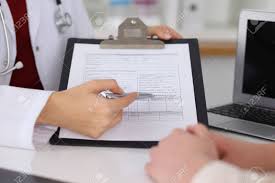 Close Up Of A Female Doctor Pointing Into An Application Form