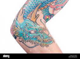 Une vue d'un bleu/vert tatouage de dragon dans le style japonais sur l'avant -bras, le coude et le biceps d'un homme de race blanche isolée sur un wh  Photo Stock - Alamy