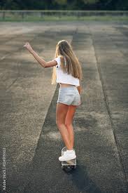 Cute beautiful young and sexy teen girl in a white T-shirt, short shorts  and white sneakers ride a skateboard Stock Photo | Adobe Stock