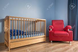 Light Blue Baby Room With Simple Cot Red Armchair And Wooden