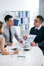 Financial Manager Explaining Business Chart To Coworkers At Meeting