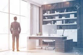 Rear View Of A Company Ceo Standing In His Dark Wood Office With