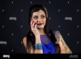 smiling beautiful indian girl calling with smart phone. young female model  wears jewelry sets and traditional blue clothes Stock Photo - Alamy
