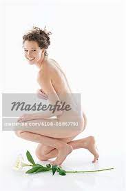 Nackte Frau kniend neben eine Blume und Lächeln - Stockbilder - Masterfile  - Premium RF Lizenzfrei, Bildnummer: 6108-05867791