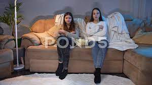 Two girls sitting on sofa at living room... | Stock Video | Pond5